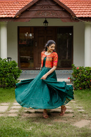 Ethnic dresses redefined: luxurious green silk paired with an ornate red brocade jacket for traditional events.